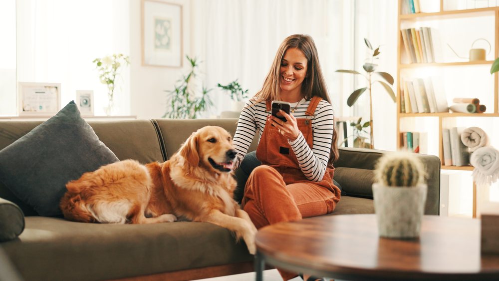 A business owner checking a booking on her phone, golden retriever beside her